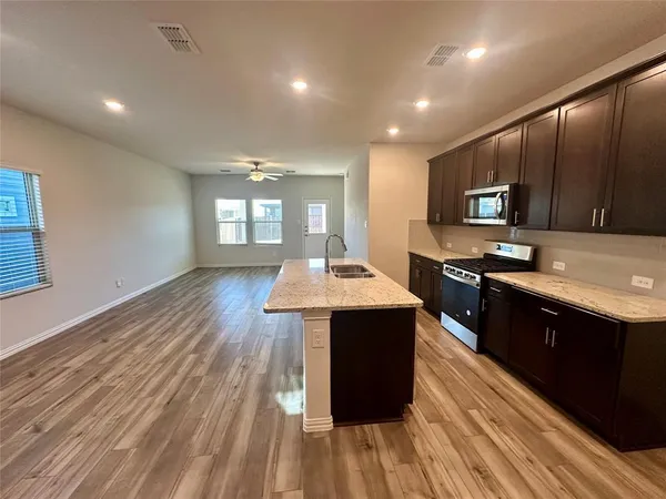 a kitchen with stainless steel appliances granite countertop a stove a sink dishwasher and a refrigerator with wooden floor