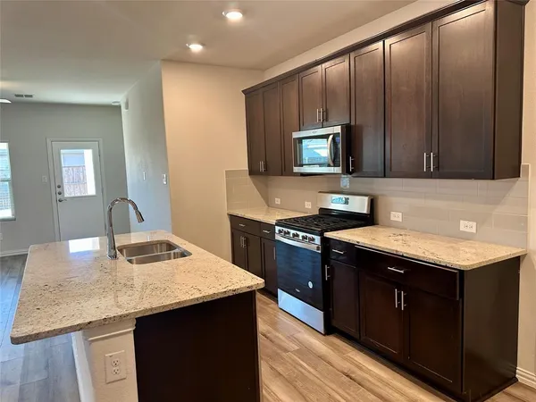 a kitchen with a sink stove top oven and refrigerator