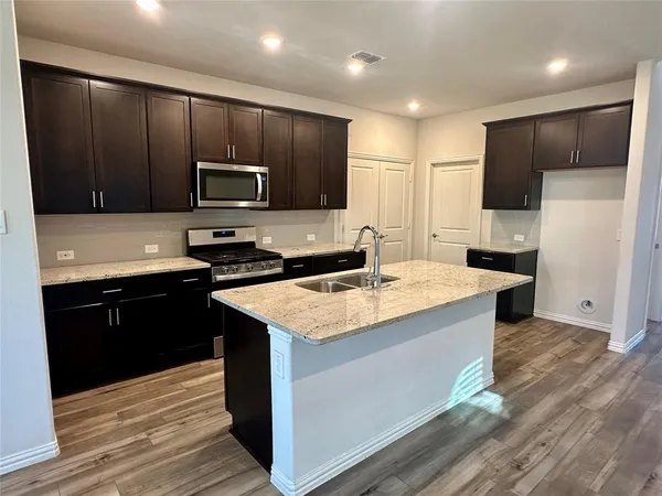 an empty room with wooden floor chandelier and windows