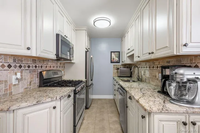 a kitchen with granite countertop a sink a stove and cabinets