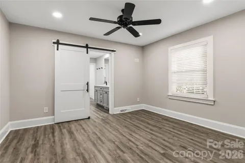 a view of empty room with wooden floor and fan