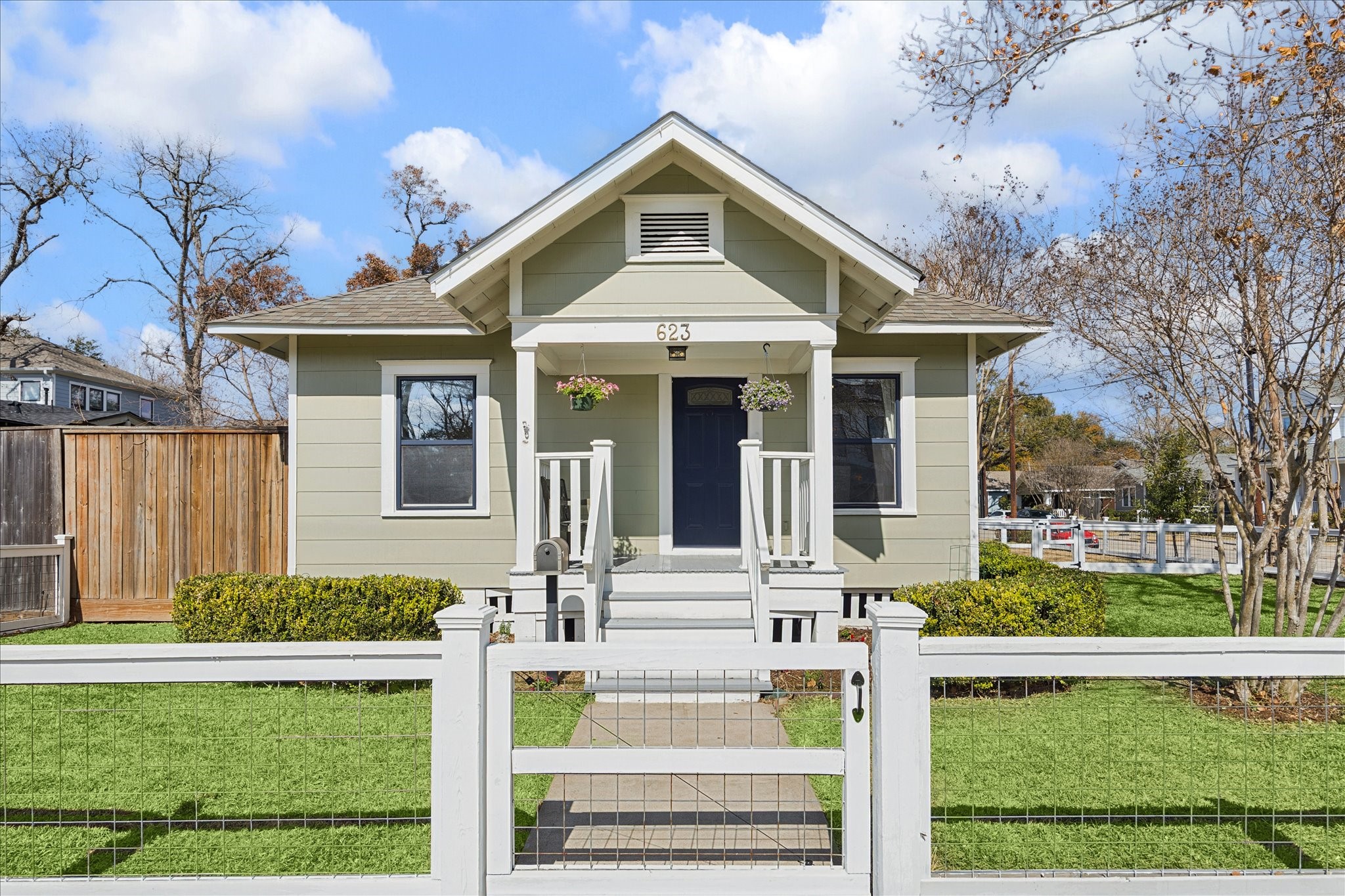 Charming Heights bungalow with welcoming front porch, classic gabled roofline, and beautifully maintained landscaping behind a fenced front yard.