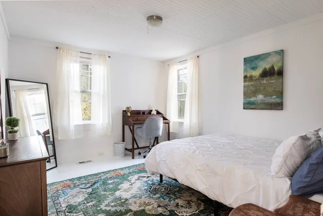 a bedroom with a bed a couch and large window