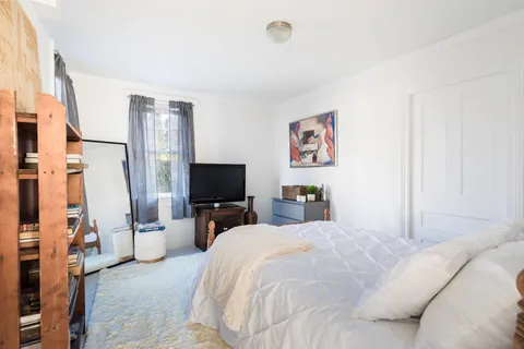 a bedroom with a bed and a flat tv screen on the dresser