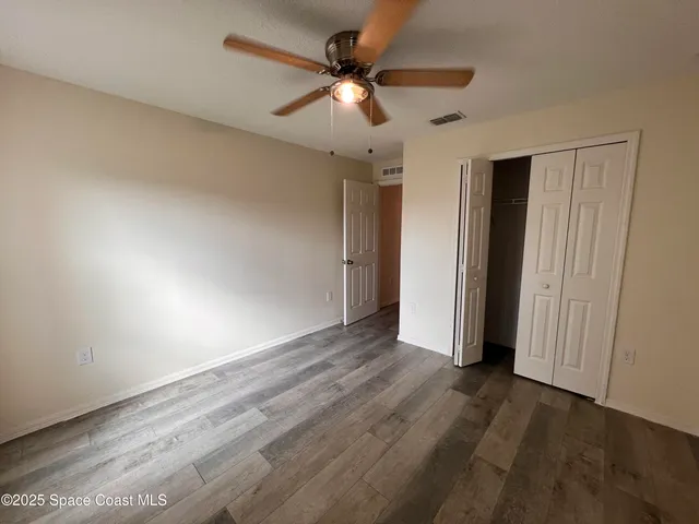 an empty room with wooden floor ceiling fan and window