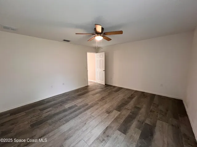 a view of a room with wooden floor and a ceiling fan