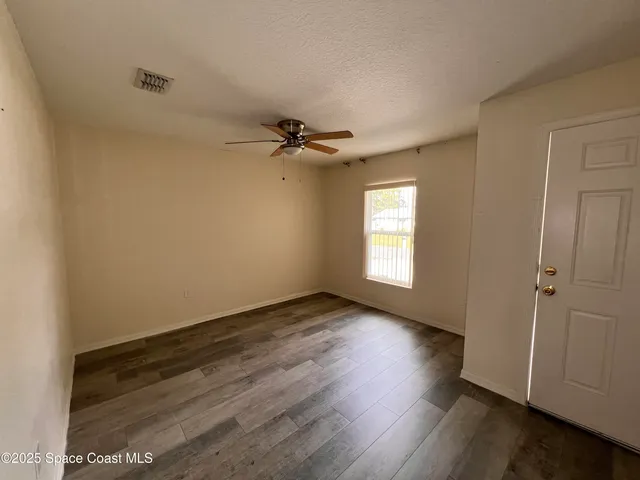 a view of an empty room with a window and wooden floor