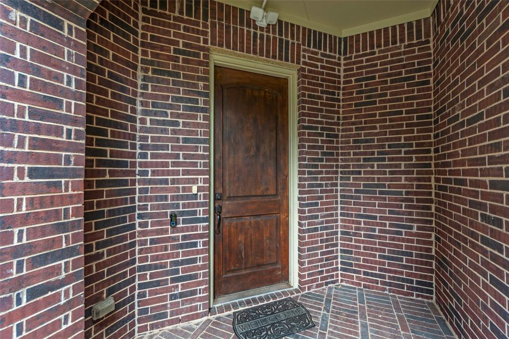 8607 Calvin Road Irving, TX 75063 - Photo 7 of 40 Rich brick exterior walls with a detailed wood entry door, complemented by light trim and a patterned brick floor