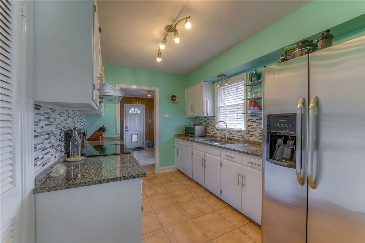 The kitchen is bright and crisp with white cabinets, granite tops, and cool backsplash