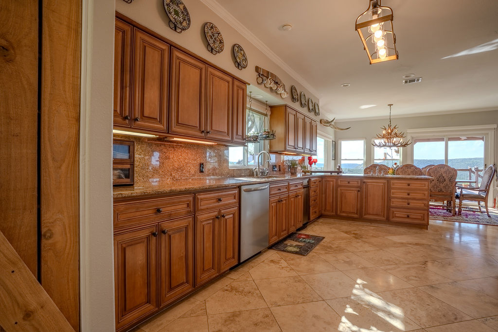 1950 Estrellita Ranch Road Canyon Lake, TX 78133 - Photo 16 of 34 a kitchen with stainless steel appliances kitchen island granite countertop a refrigerator and wooden cabinets