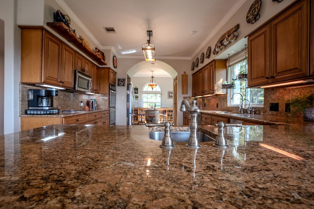 1950 Estrellita Ranch Road Canyon Lake, TX 78133 - Photo 17 of 34 a kitchen with stainless steel appliances granite countertop a stove top oven a refrigerator a dining table and chairs with wooden floor