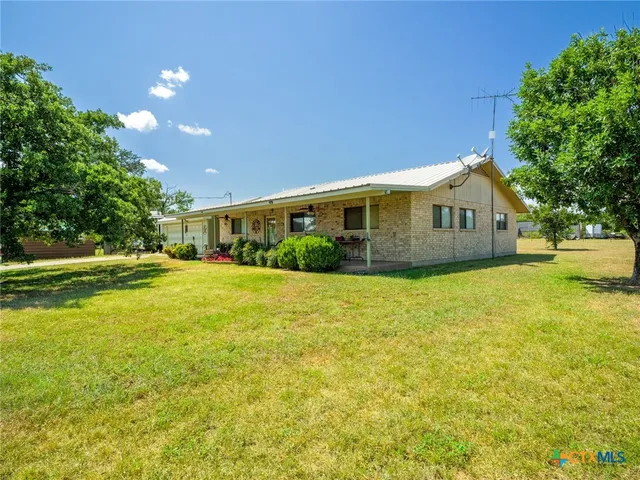 a view of house with yard and trees in the background