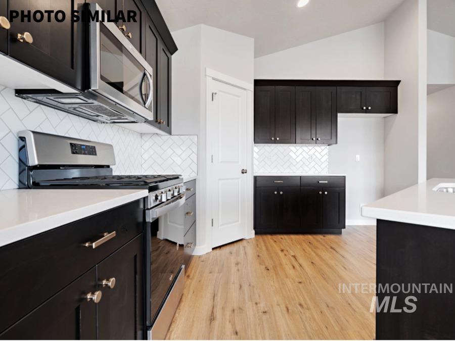 925 Twilight Weiser, ID 83672 - Photo 12 of 31 Kitchen featuring dark wood-finish cabinetry, light countertops, a white herringbone tile backsplash, stainless steel appliances, and wood-finish flooring