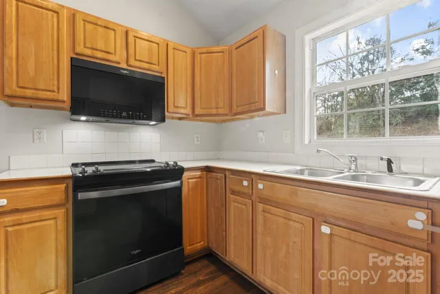 a kitchen with granite countertop a sink stove and microwave