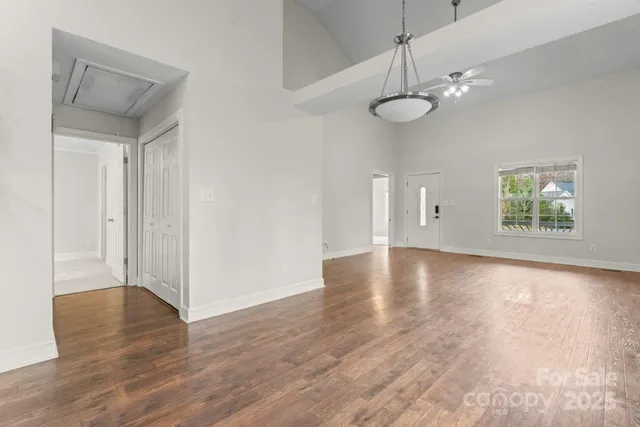 a view of an empty room with wooden floor and fan