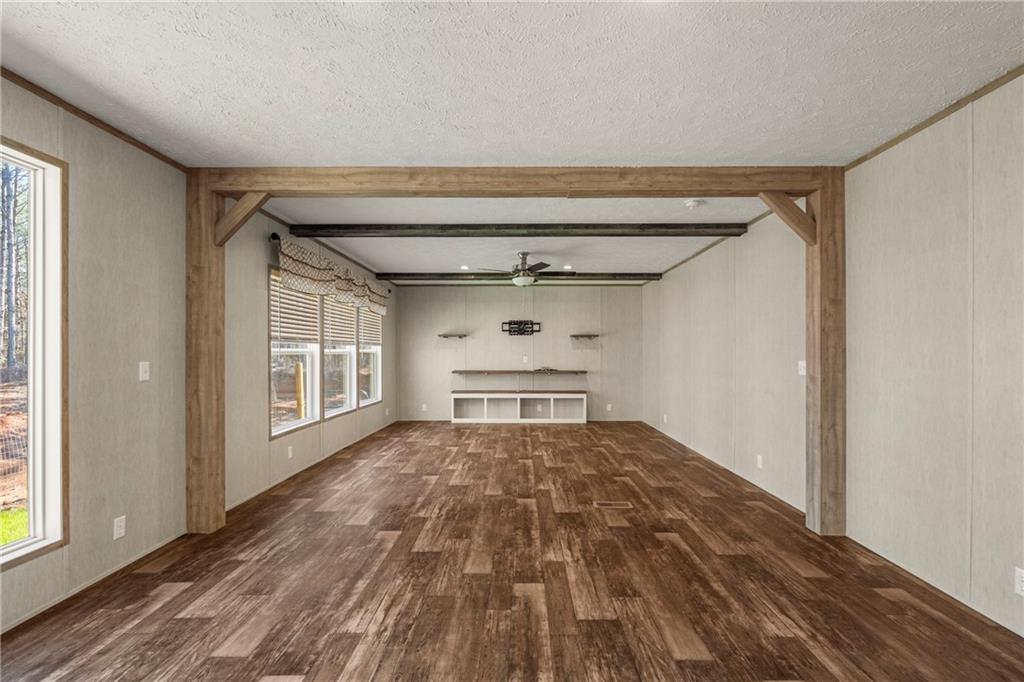 15 Rutledge Road Seale, AL 36875 - Photo 6 of 25 Unfurnished living room with dark wood finished floors, a ceiling fan, a textured ceiling, and beamed ceiling
