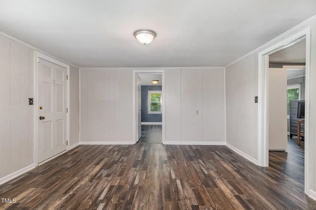 a view of an empty room with wooden floor and a bathroom