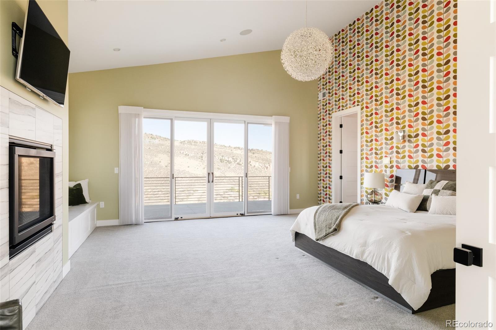 15480 Dinosaur Ridge Road Morrison, CO 80465 - Photo 23 of 50 a spacious bedroom with a bed and a television