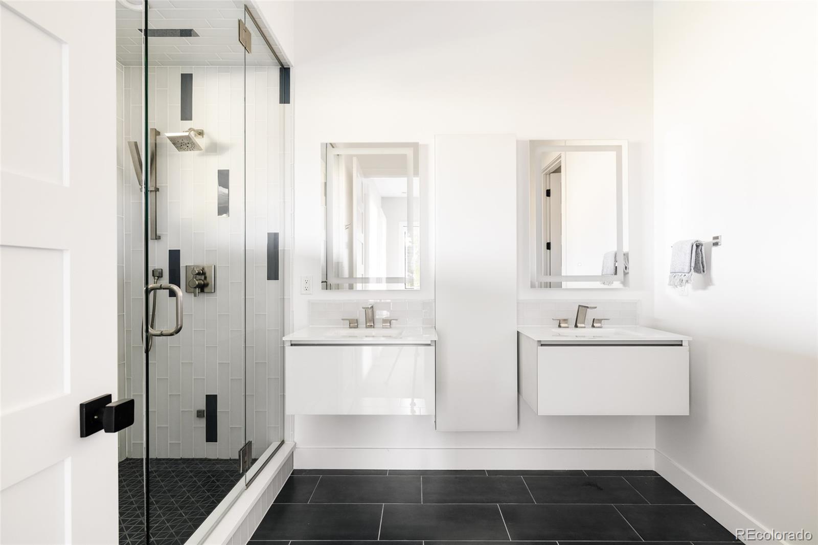 15480 Dinosaur Ridge Road Morrison, CO 80465 - Photo 47 of 50 a bathroom with a double vanity sink a mirror and a shower