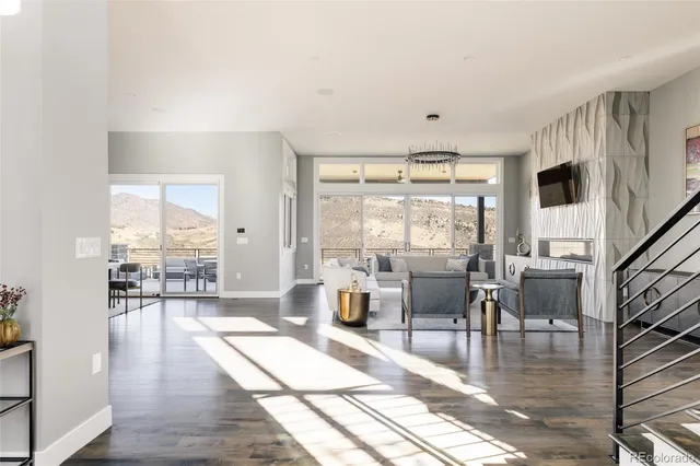 a living room with furniture large window and wooden floor