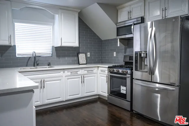 a kitchen with stainless steel appliances granite countertop a refrigerator sink and stove