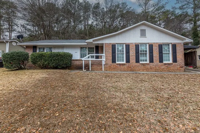 a view of a house with a yard and large trees