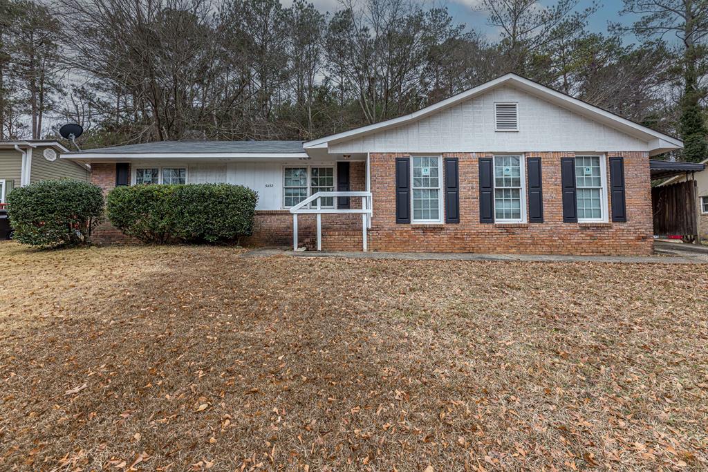 a view of a house with a yard and large trees
