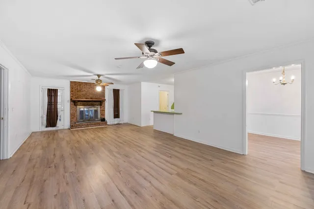 an empty room with wooden floor a ceiling fan and windows