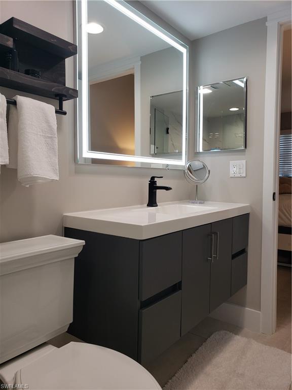 5435 Rattlesnake Hammock Road, Unit E102 Naples, FL 34113 - Photo 13 of 32 a bathroom with a sink toilet and mirror