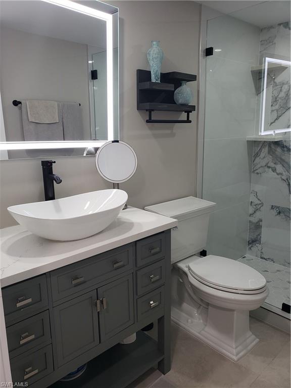 5435 Rattlesnake Hammock Road, Unit E102 Naples, FL 34113 - Photo 19 of 32 a bathroom with a granite countertop toilet sink and mirror