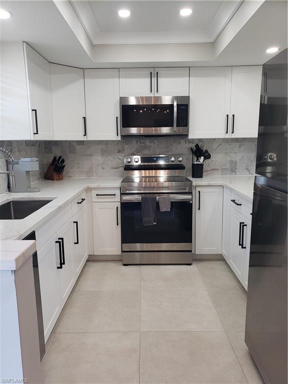 5435 Rattlesnake Hammock Road, Unit E102 Naples, FL 34113 - Photo 2 of 32 a kitchen with stainless steel appliances granite countertop a stove top oven microwave and cabinets