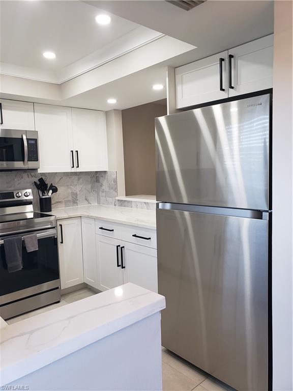 5435 Rattlesnake Hammock Road, Unit E102 Naples, FL 34113 - Photo 3 of 32 a kitchen with stainless steel appliances granite countertop a refrigerator a sink and a stove