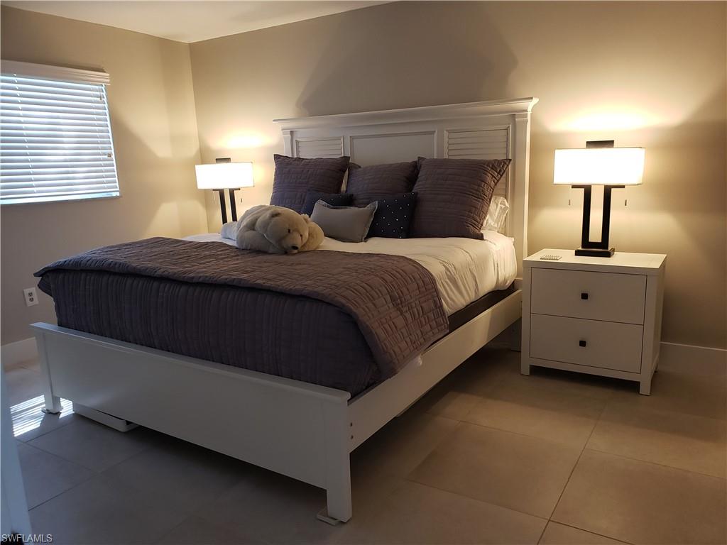 5435 Rattlesnake Hammock Road, Unit E102 Naples, FL 34113 - Photo 10 of 32 a bedroom with a bed and a lamp