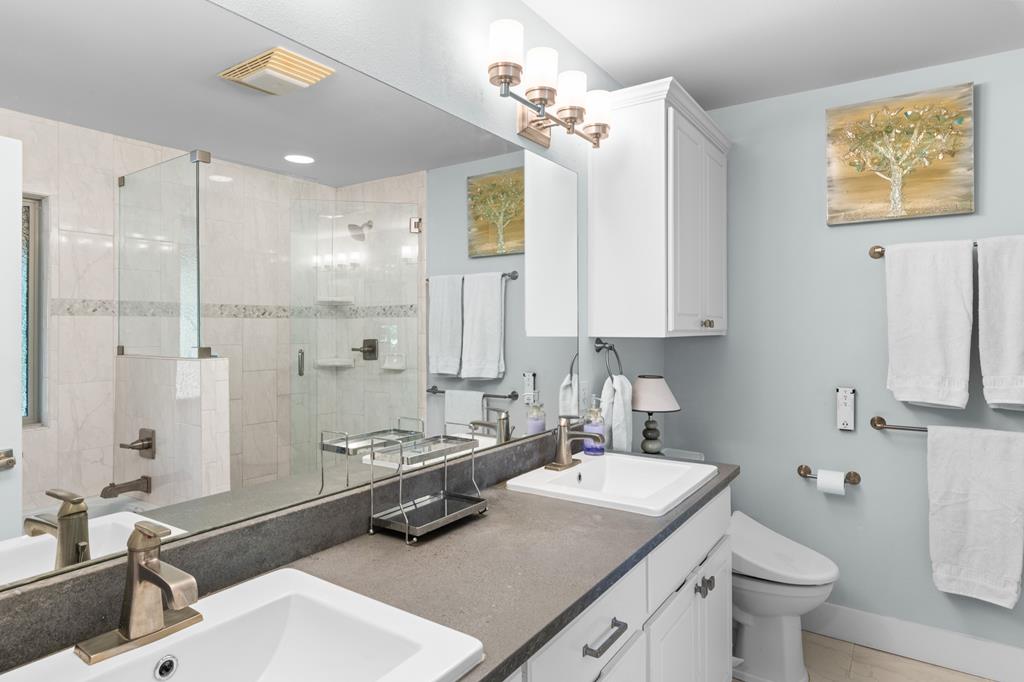 290 Cardinal Hill Road Ingram, TX 78025 - Photo 22 of 57 a bathroom with a granite countertop sink a toilet a mirror and shower