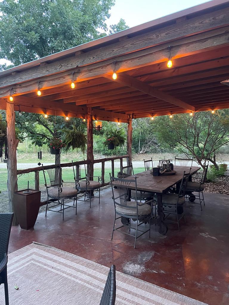 290 Cardinal Hill Road Ingram, TX 78025 - Photo 52 of 57 a view of a patio with a dining table and chairs with wooden floor and fence