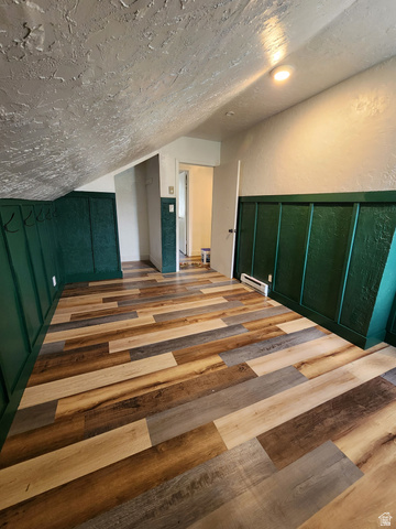 320 South State Street Preston, ID 83263 - Photo 11 of 20 Bedroom with wood finished floors, a textured wall, a baseboard heating unit, and a decorative wall