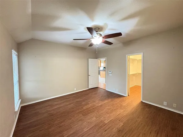 an empty room with wooden floor and a ceiling fan