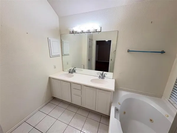 a bathroom with a double vanity sink mirror and bathtub