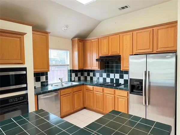 a kitchen with stainless steel appliances granite countertop a refrigerator cabinets and a stove top oven