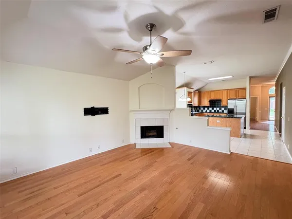 a view of a livingroom with a fireplace a chandelier fan and wooden floor