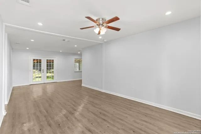 an empty room with wooden floor and windows