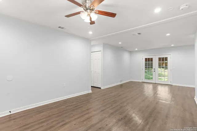 an empty room with wooden floor and windows