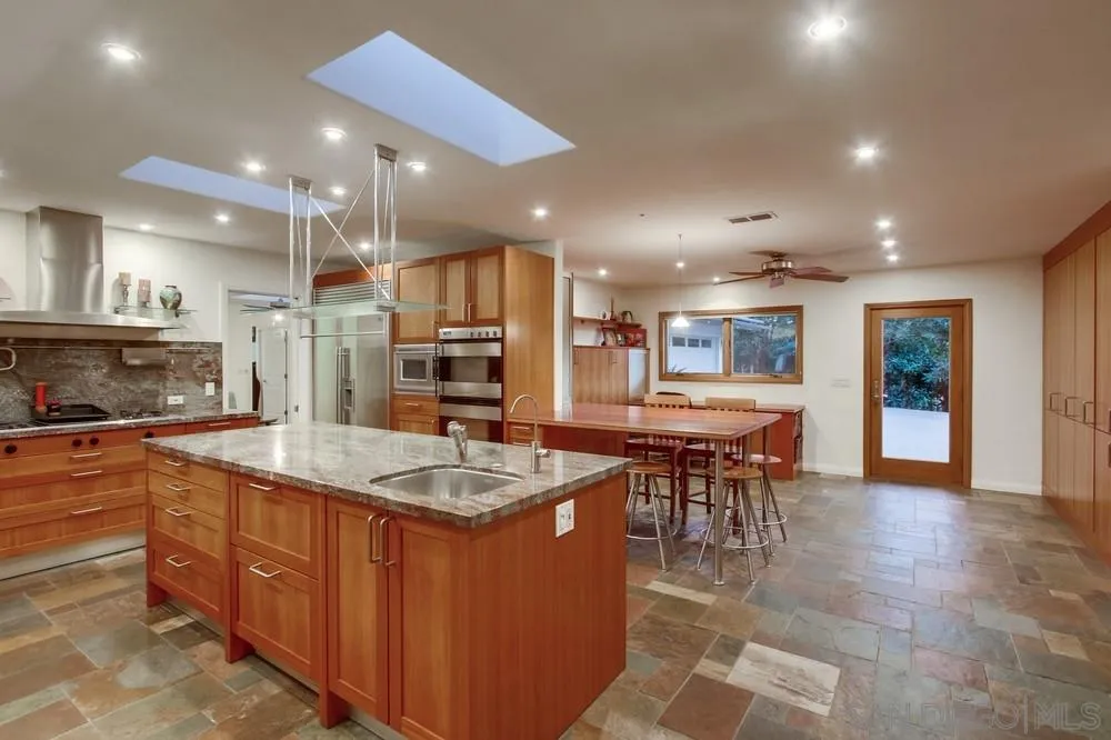13401 Stone Canyon Road Poway, CA 92064 - Photo 11 of 25 a kitchen with stainless steel appliances granite countertop table chairs sink and cabinets