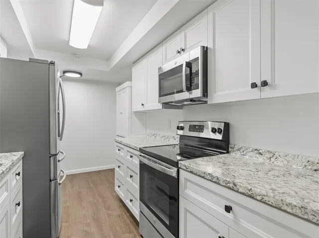 a kitchen with stainless steel appliances granite countertop white cabinets and a granite counter tops