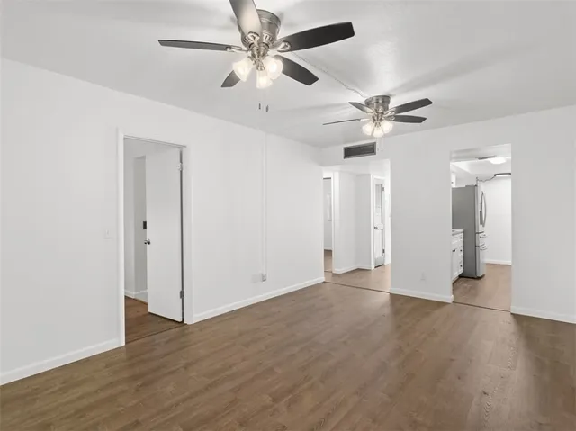 an empty room with wooden floor ceiling fan and window