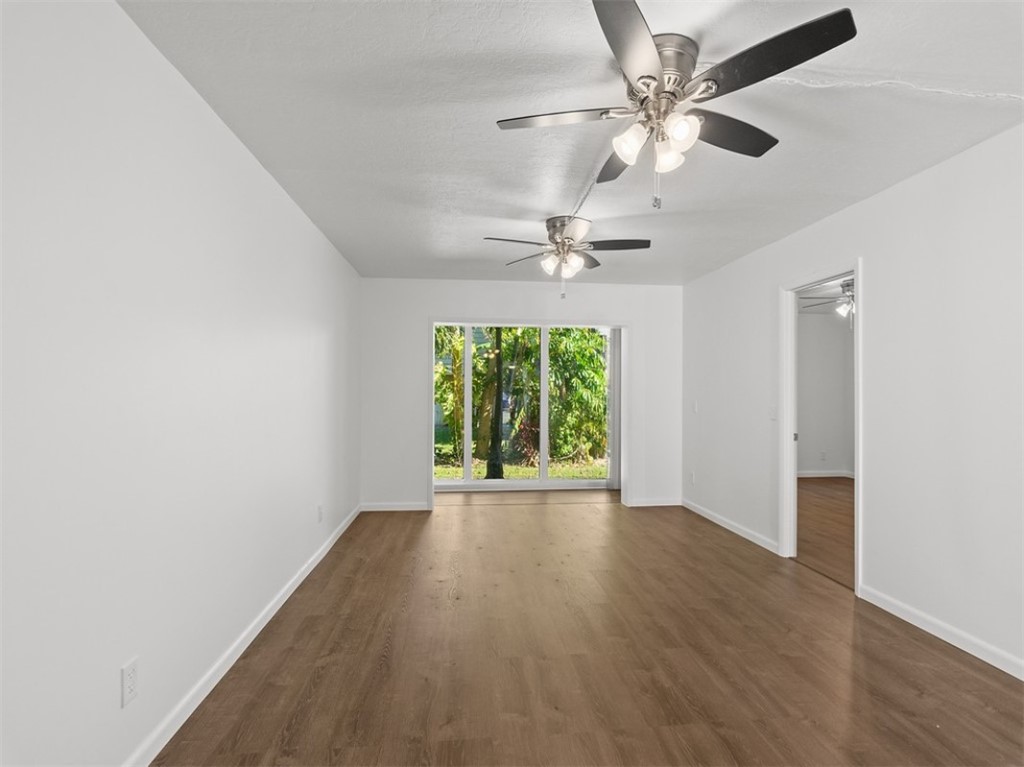 1166 6th Avenue, Unit C5 Vero Beach, FL 32960 - Photo 20 of 34 an empty room with wooden floor chandelier fan and windows