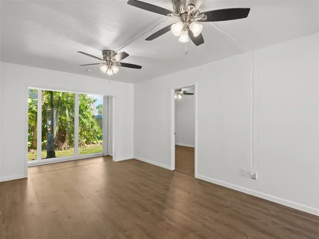 an empty room with wooden floor fan and windows