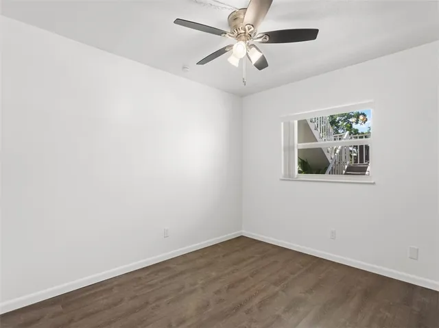 an empty room with wooden floor and ceiling fan