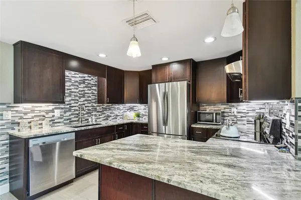 a kitchen with stainless steel appliances kitchen island granite countertop a refrigerator and a stove top oven