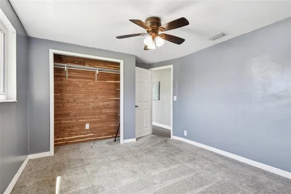 an empty room with closet and ceiling fan